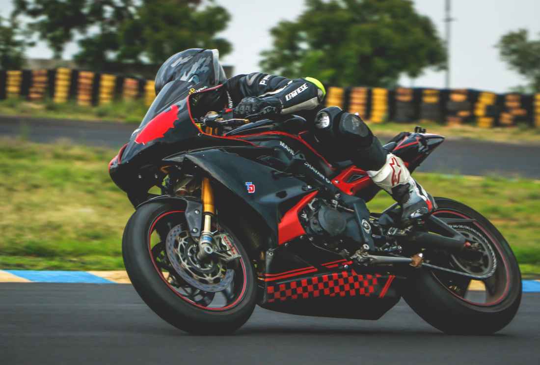 man with black alpinestar racing suit riding black and red sports bike