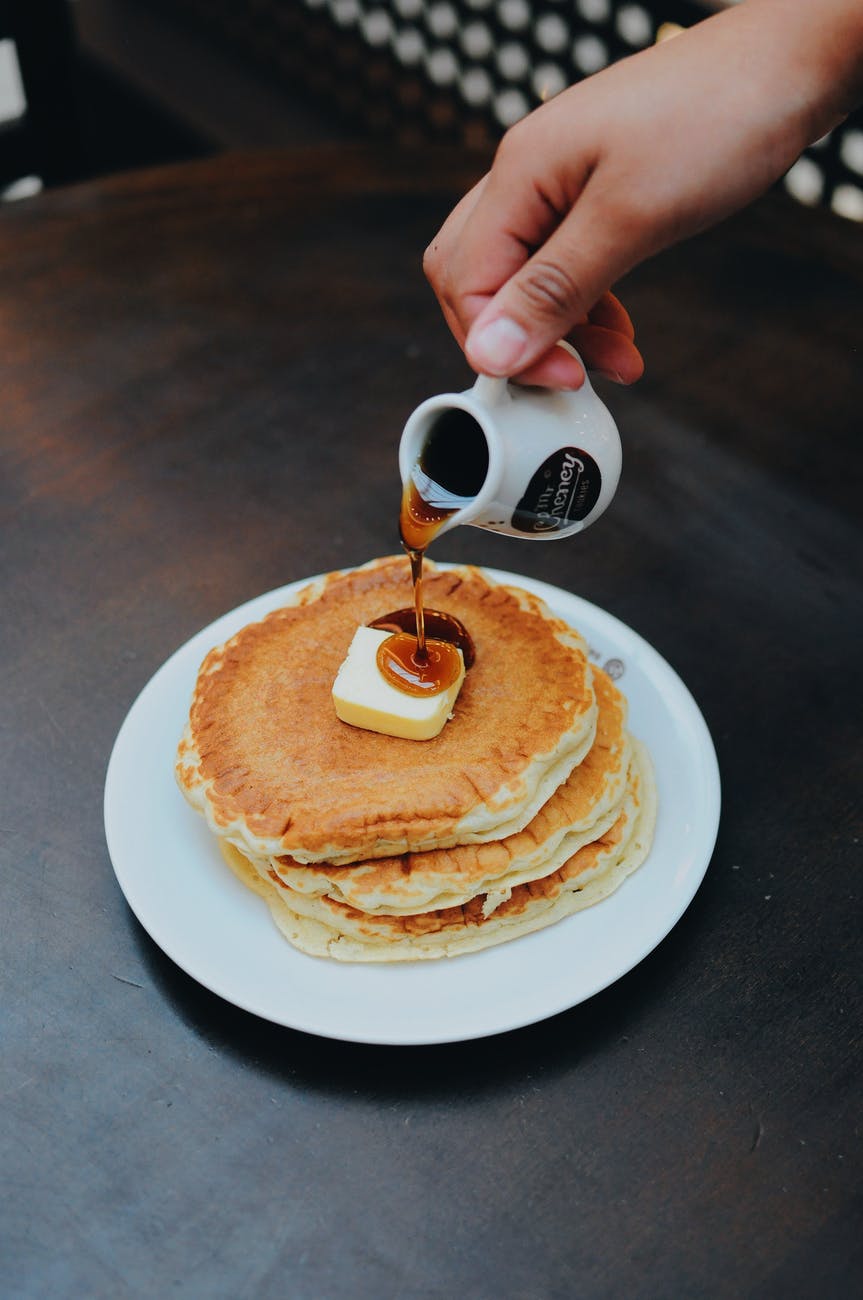 photo of a person pouring syrup on pancake