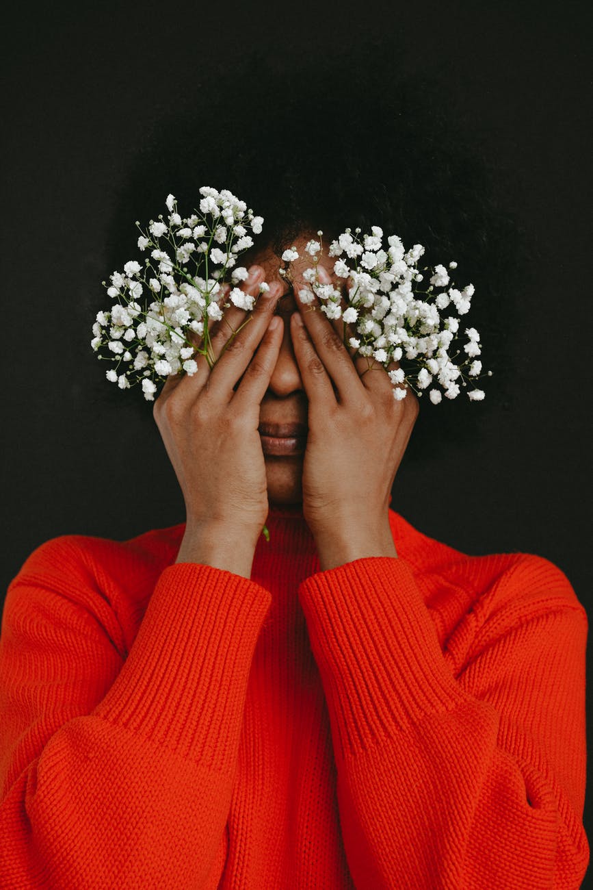person in red long sleeve shirt holding white flowers