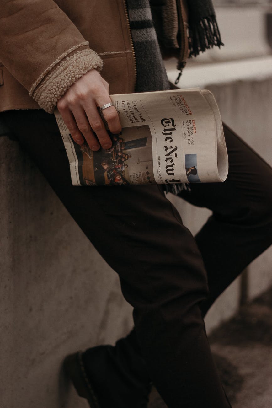 person in brown coat holding a news paper