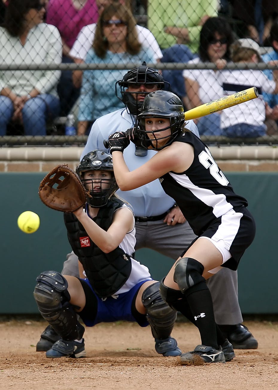two female in baseball gears in stadium ready to catch and swing baseball